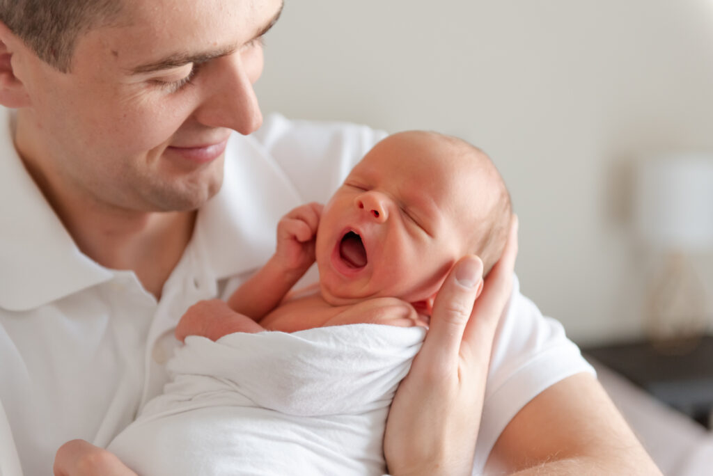 Father holding newborn baby in a quiet moment during in-home newborn photography session in St. George