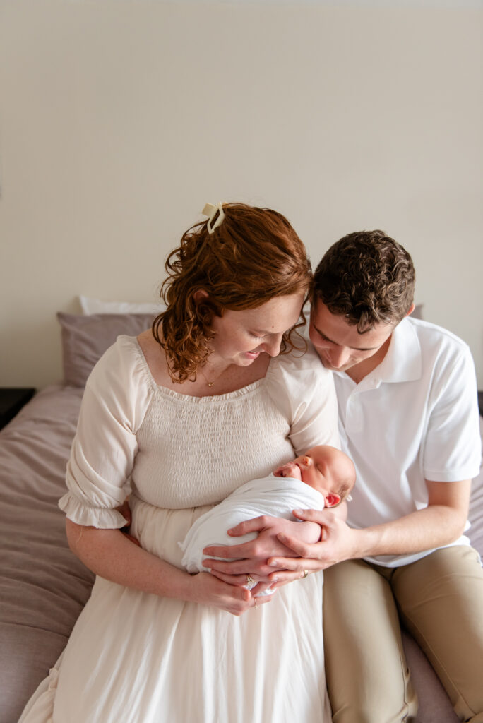 New parents cuddling on bed during a relaxed in-home newborn session in St. George