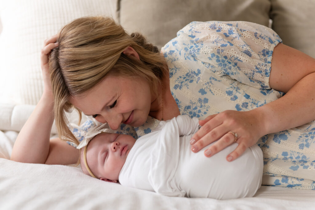 Mother snuggled up with newborn on bed in St. George, Utah