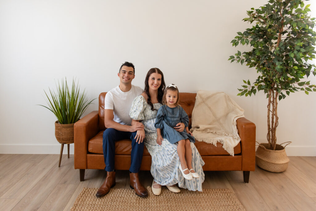 Family of three posing together in cozy Utah studio maternity session