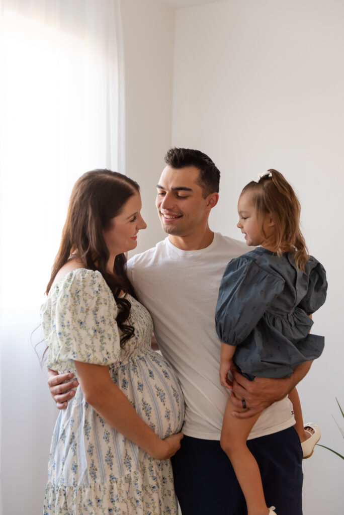 Family of three posing together in cozy Utah studio maternity session