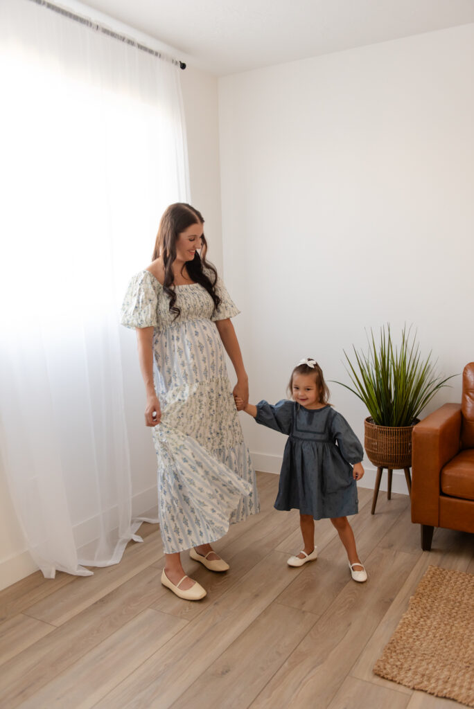 Studio maternity session in Hurricane Utah – mom twirling daughter in natural window light