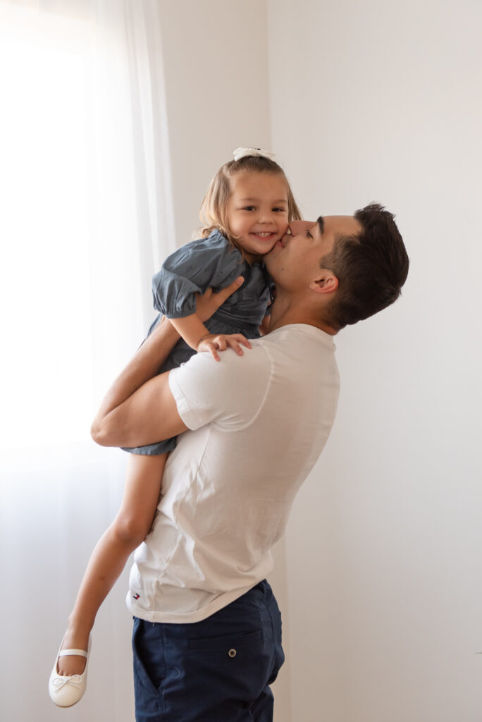 Family maternity photos in Southern Utah – dad kissing toddler girl on the cheek with laughter