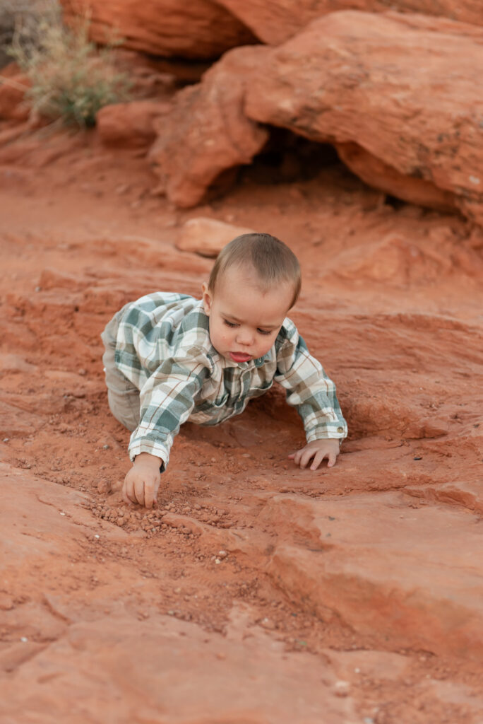 Toddler exploring red rocks and sand in st. george