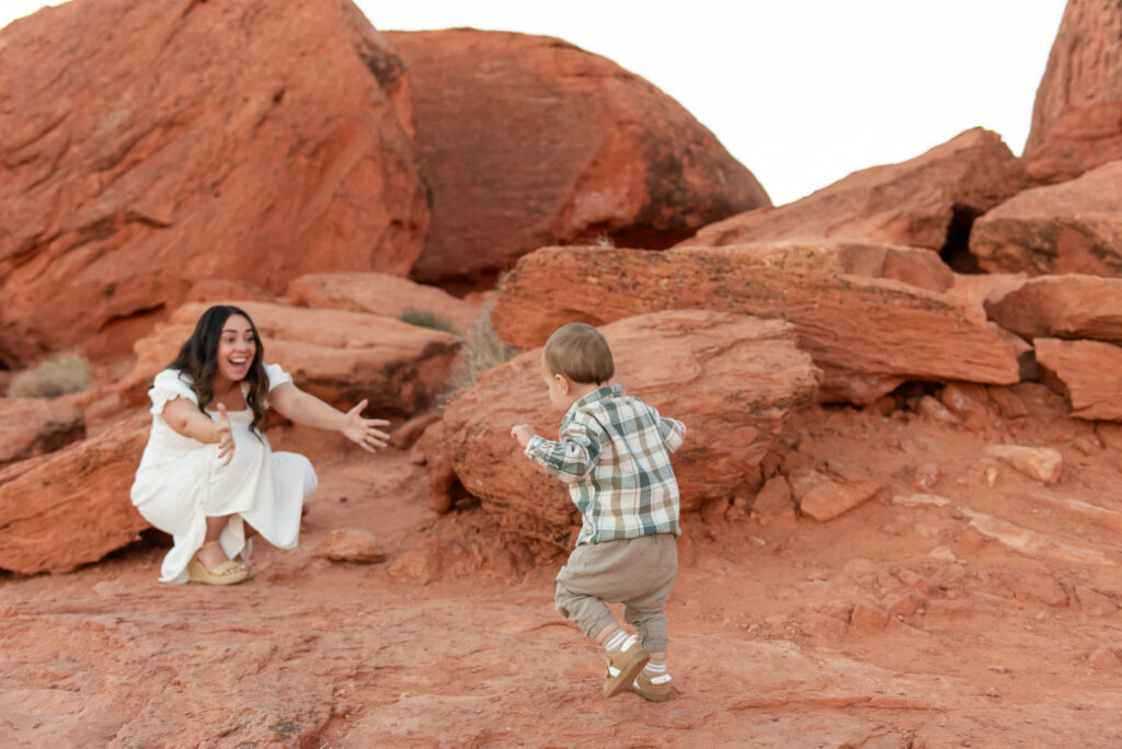 Toddler walking to mom on red rocks