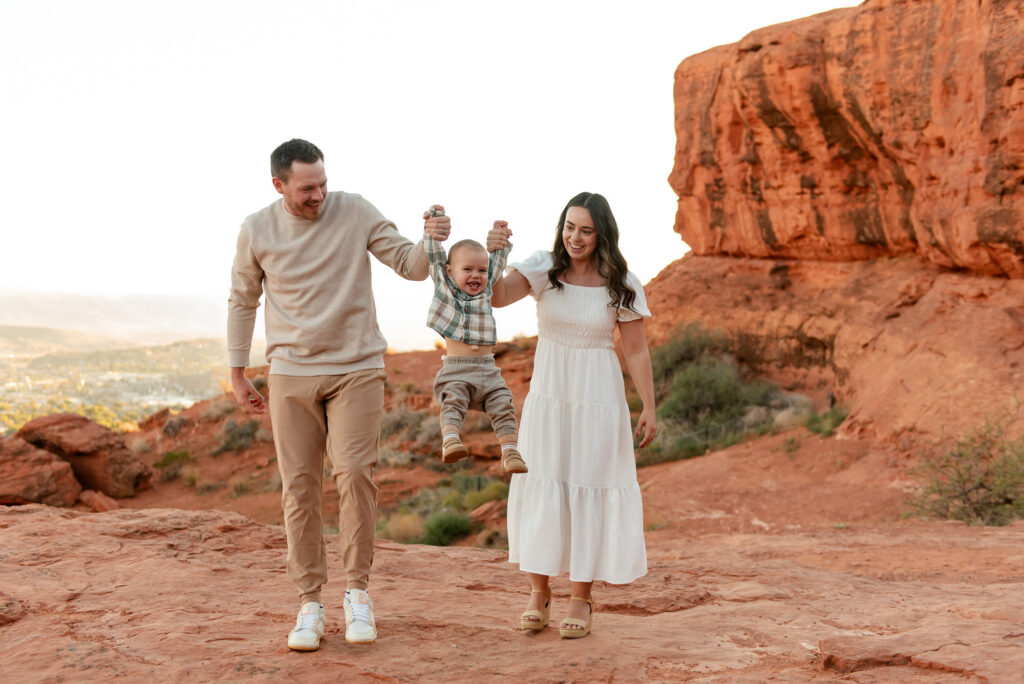 Parents swinging toddler in air at red rocks photo session
