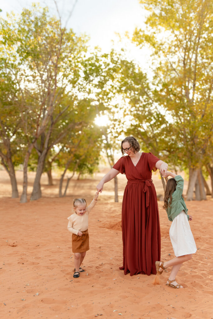 Mother twirling daughters in sand 